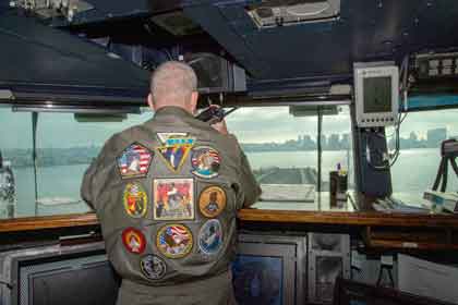 PACIFIC OCEAN (Sept. 15, 2025) U.S. Navy Capt. Brian Schrum, commanding officer of the Nimitz-class aircraft carrier USS Theodore Roosevelt (CVN 71), oversees operations in the pilot house as the ship pulls into San Diego, Sept. 15, 2025. Theodore Roosevelt, flagship of Carrier Strike Group (CSG) 9, is underway conducting exercises to bolster strike group readiness and capability in the U.S. 3rd Fleet area of operations. U.S. Navy photo by MC2 Jadyn Beavers.